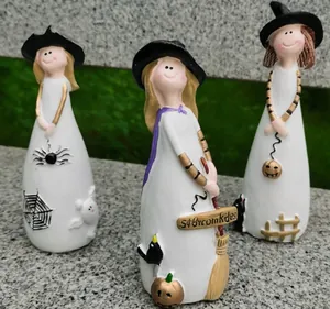 Detailed view of three resin witch figurines with pumpkin, broom, and spider accents