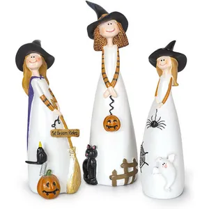 Detailed close-up of three resin witch figurines with pumpkins and black cats for Halloween
