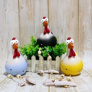 Close-up of three resin roosters with long rope legs and big eyes on wood background