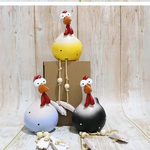 Detailed view of three resin big-eyed roosters with polka dots and long hanging rope legs