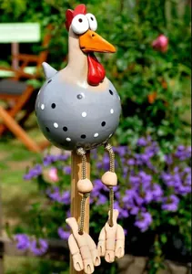 Garden chicken figurine with black dots and long hanging legs on a wooden table