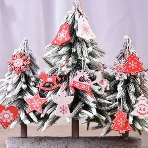 Creative Christmas wood ornaments with bells and elk hanging on snow-covered trees