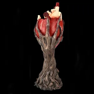 Escultura gótica de corazón anatómico en resina sobre base de rama con rosa y vela