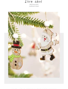 Detail of wooden Santa and snowman ornaments hanging on a festive Christmas tree branch