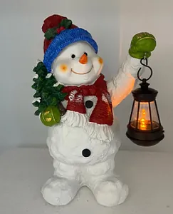 Detailaufnahme einer Schneemannfigur aus Harz mit Tannenbaum und leuchtender Laterne