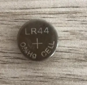 Detail shot of LR44 button cell battery for Halloween floating fireball prop on wood surface