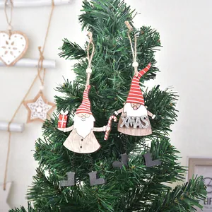 Deux gnomes de Noël en bois avec signes XMAS pailletés suspendus à un sapin de Noël