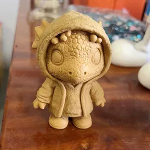 Detail of 3D printed yellow dinosaur figurine in hoodie on a wooden surface
