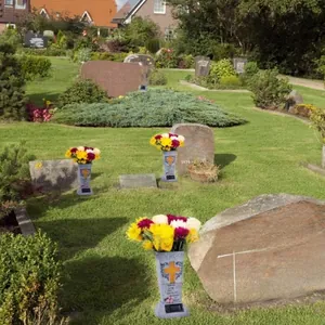 Solar powered cemetery flower vase with orange cross relief and solar panel on lawn