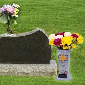 Detailed solar grave vase with golden cross and rose carving on green grass lawn