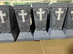 Detail of stone-texture resin memorial cross with heart relief and engraved tribute text