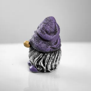 Macro detail of resin gnome sculpture with purple textured hat and golden nose