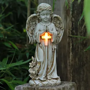 Close-up of solar resin angel statue with glowing cross for garden memorial decor