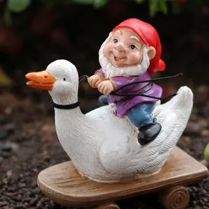 Gartenzwerg auf weißer Gans auf einem Holzwagen, Gartenfigur aus Kunstharz außen