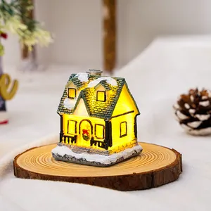 Dettaglio di casetta di Natale luminosa in resina con luci LED calde su base di legno