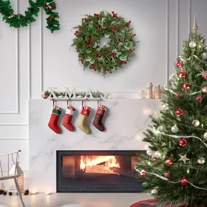 Decorazioni natalizie per camino con calze, ghirlanda di bacche e albero addobbato