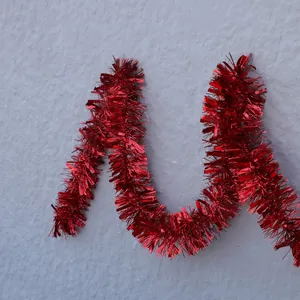 Guirlande métallique rouge brillante pour décoration de Noël sur un mur texturé gris