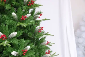 Detailed close-up of artificial Christmas tree branches with red berries and snow flocking