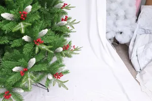 Close-up of green flocked Christmas tree with red berries and snowy pine cones detail