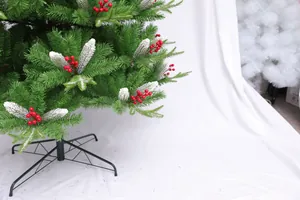 Detail of green Christmas tree branches with red berries, snow texture, and metal stand