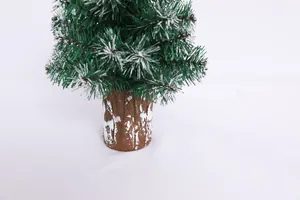 Close-up of mini Christmas tree featuring snow-tipped green needles and a rustic wood base