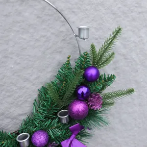 Detail eines Weihnachtskranzes mit lila Ornamenten, Zapfen und Kerzenhaltern aus Metall
