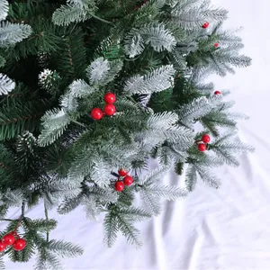 Dettaglio di rami di albero di Natale in PVC con fiocchi di neve e bacche rosse