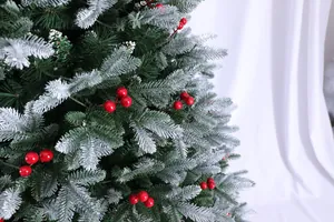 Dettaglio di aghi di pino artificiali verdi con fiocchi di neve e bacche rosse