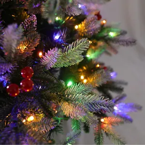 Dettaglio di ramo di albero di Natale con luci LED colorate, bacche rosse e neve finta