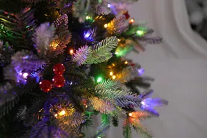 Dettaglio ravvicinato dell'albero di Natale innevato con luci LED colorate e bacche