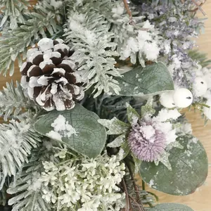 Detailed view of snowy cedar branches, eucalyptus leaves, and pine cones on a wooden surface