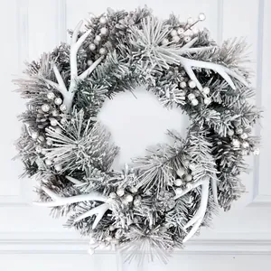 Detail eines beflockten Geweih-Weihnachtskranzes mit weißen Beeren und Frostnadeln