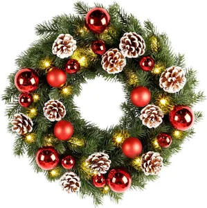 Close-up of Christmas wreath with red ornaments, frosted pine cones and warm LED lights
