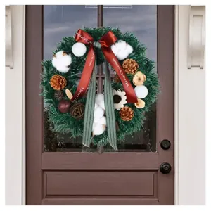 Détail d'une couronne de Noël avec nœud rouge et pommes de pin sur porte en bois