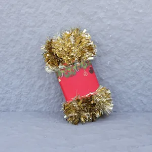 Detail of shiny light gold Christmas tinsel garland with festive red cardboard packaging