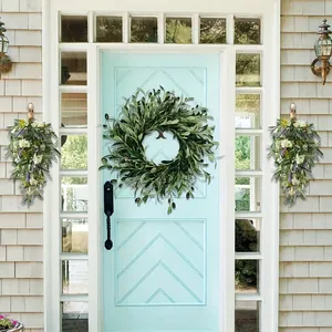 Detailed view of the artificial olive leaf wreath with green foliage on a blue door