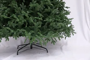 Detail of green artificial Christmas tree needles and stable black metal four-leg stand