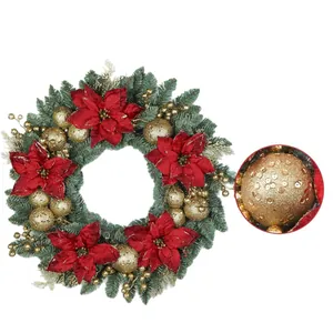 Ghirlanda di Natale con fiori di stella di Natale rossi e palline dorate su aghi di pino verdi