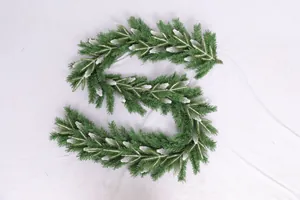 Close-up of flexible snow-flocked PE and PVC green Christmas garland on white fabric