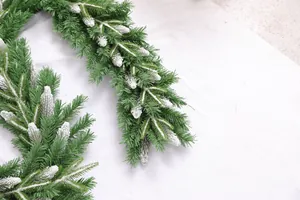 Close-up of artificial green Christmas garland with realistic white snow flocked pine needles