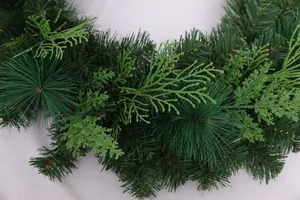 Macro detail of mixed pine needles and PVC cedar leaves on a lush green Christmas wreath