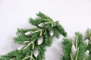 Close-up of green PE Christmas pine branch with white flocked snow and pine cones