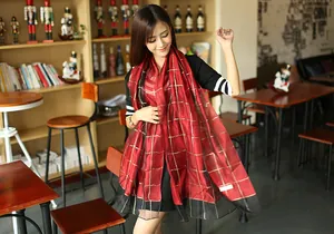 Detailed view of red and black checkered silk scarf with gold threads and brand label