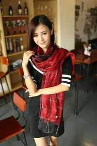 Detail of red and black silk scarf with gold grid pattern and translucent fabric ends
