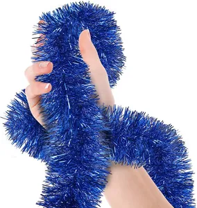 Detail view of 15m shiny blue metallic tinsel garland wrapped around hand for holiday decor