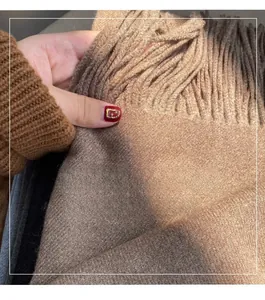 Macro detail of soft khaki cashmere-feel scarf showing thick texture and fine fringe