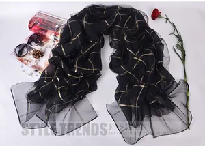 Detail of lightweight black silk scarf with golden metallic grid pattern on white table