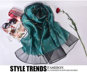 Detail of emerald green silk scarf with gold grid patterns and sheer black organza borders