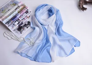 Detalle de bufanda de seda degradada azul y blanca con accesorios de moda de lujo