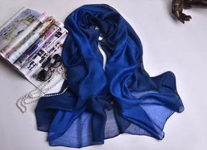 Detalle de bufanda de seda azul real con collar de perlas y accesorios de moda